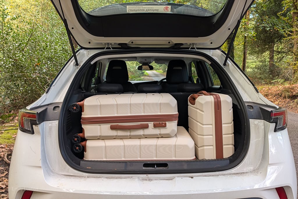 3 cream suitcases with brown trim in the boot of a white car