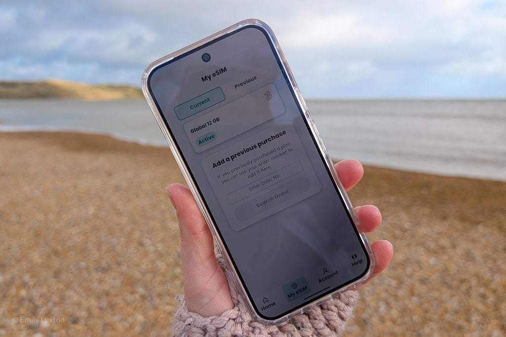 Hand holding a phone with the Sim local app showing an active global eSIM